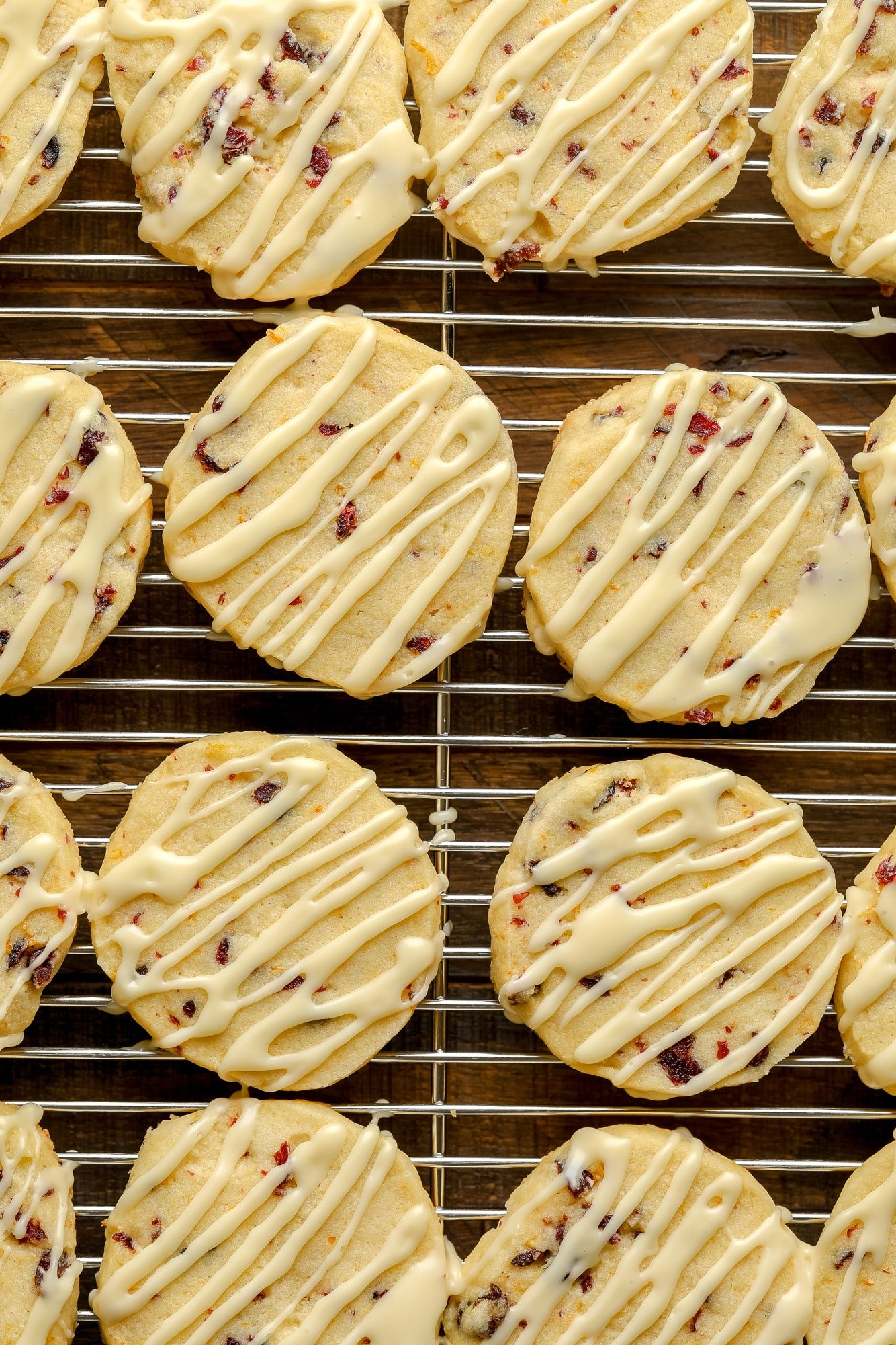 Feche os biscoitos de biscoito de cranberry laranja decorados com esmalte laranja em uma gradinha.